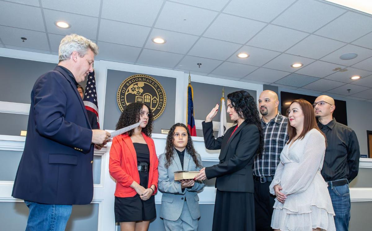 Mayor John Ernst (left) administers the Oath of Office to Sandra Bryant (center) in the company of her family.